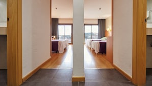Passadís d'hotel amb un mur espeillat, sòl de fusta i vistes a la ciutat a través de grans finestres.
