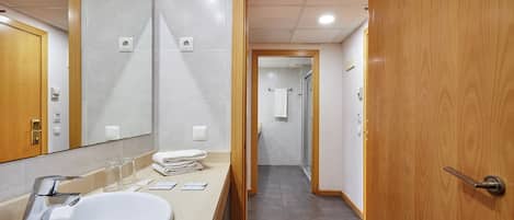 Un baño de hotel con lavamanos, espejo y puerta de madera.