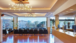 Rebedor modern d'hotel amb taulell de recepció, zona d'estar i grans finestres amb vista a la ciutat.