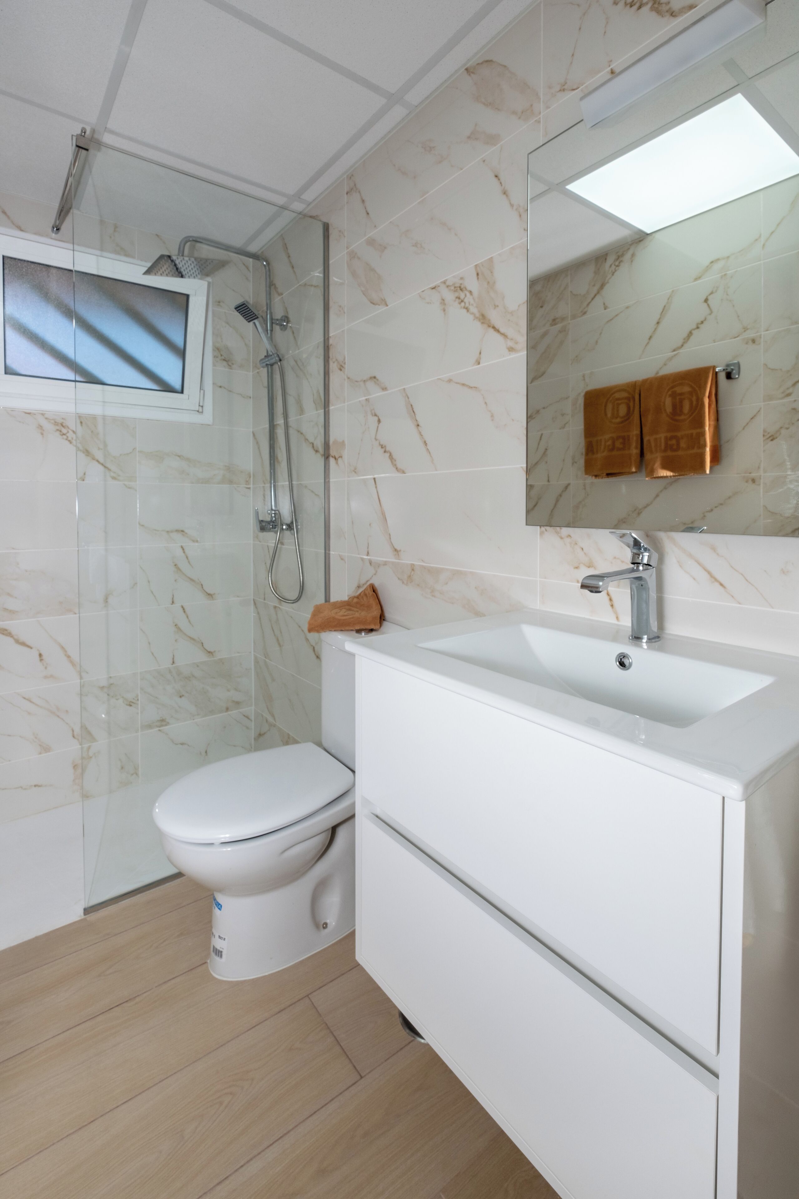 A modern bathroom with a toilet, sink, and shower.
