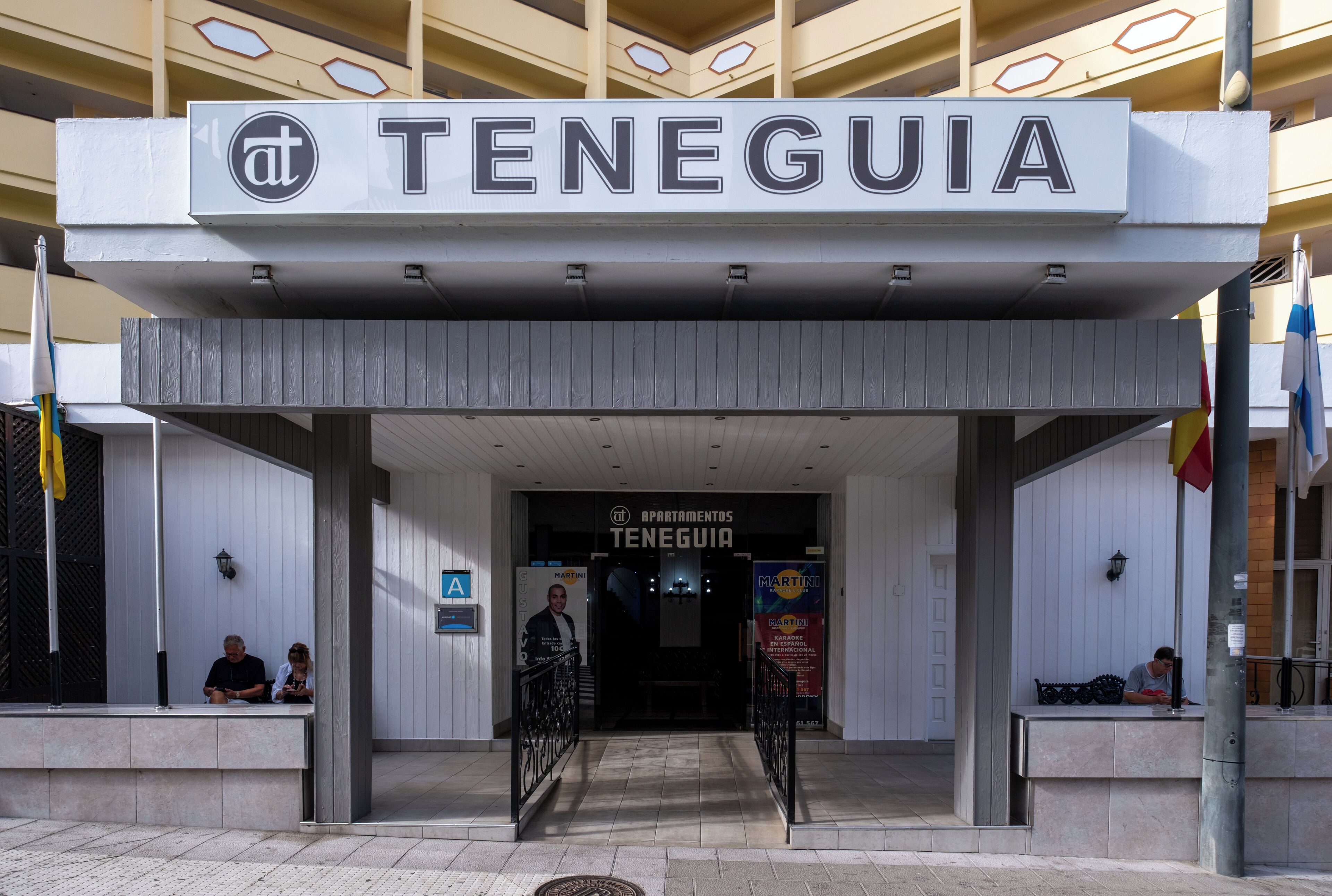 Entrada de un hotel con un letrero que dice "TENEGUIA" y un cartel para "APARTAMENTOS TENEGUIA".