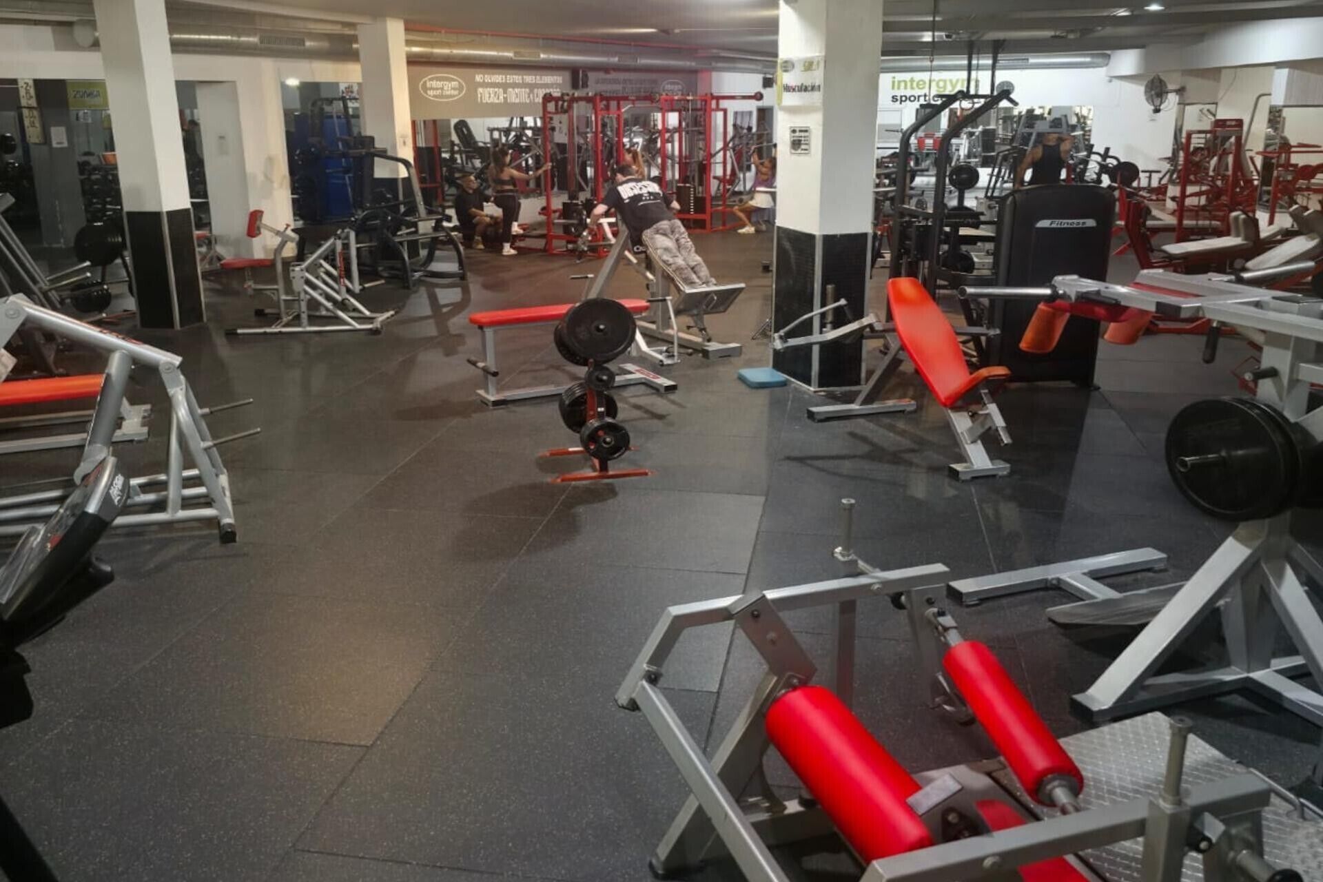 Une salle de sport équipée de divers appareils d’exercice, notamment des machines de musculation et des bancs.