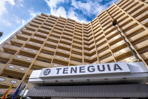 Un edificio de gran altura con un letrero que dice "TENEGUIA" y varios balcones.