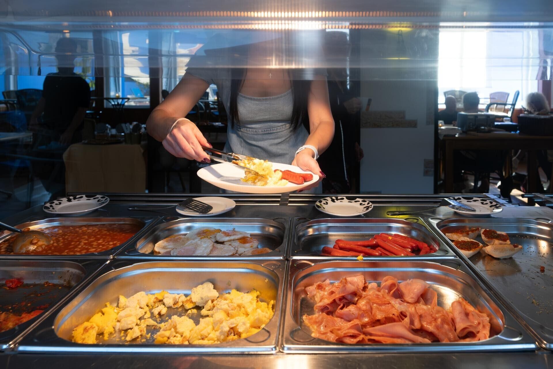 Ein Buffet mit verschiedenen Speisen, darunter Bohnen, Rührei und Schinken.
