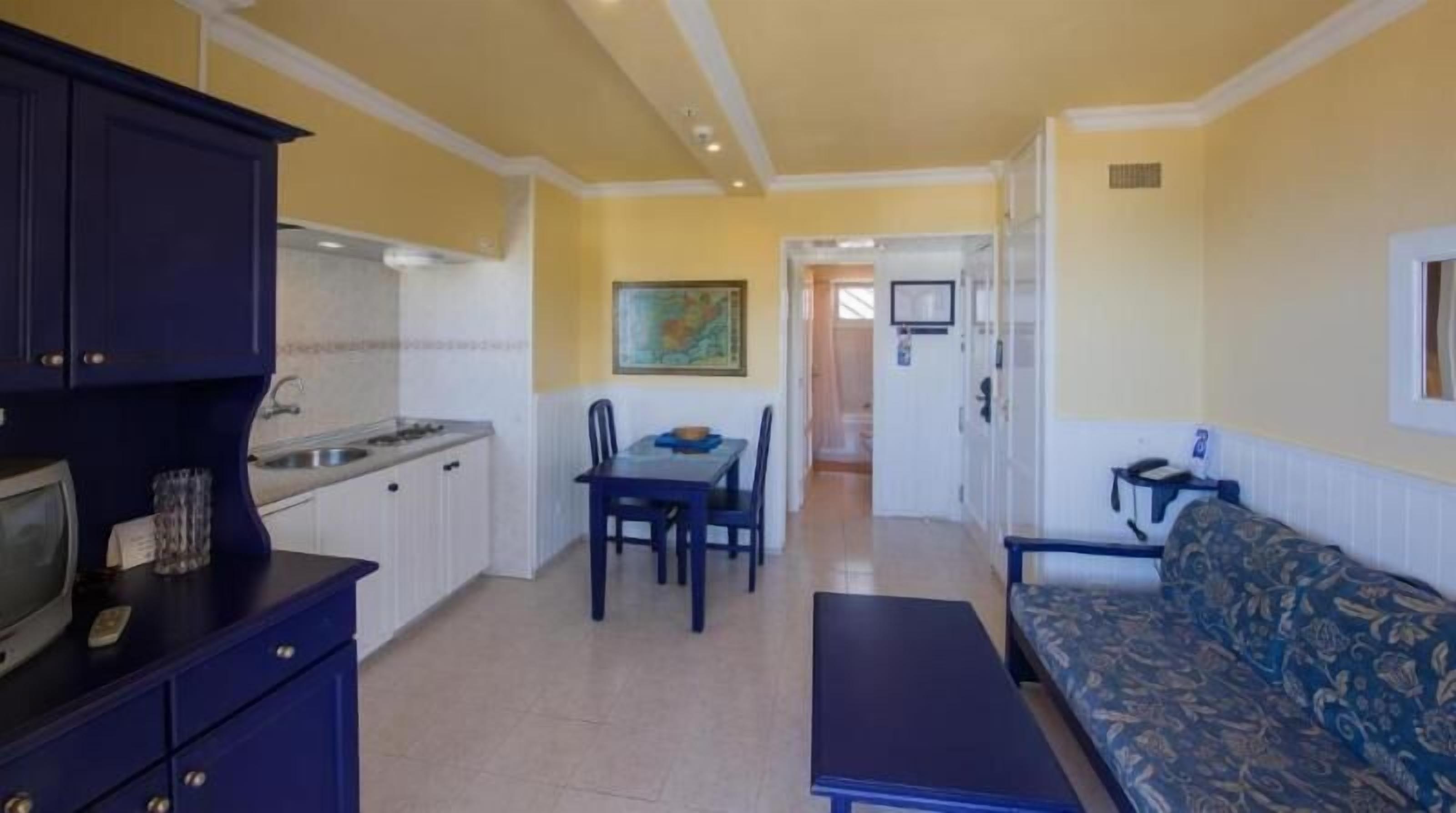 Un espace de vie compact comprenant une kitchenette, un coin repas et un canapé.