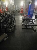 A gym with rows of dumbbells, benches, and weightlifting equipment.