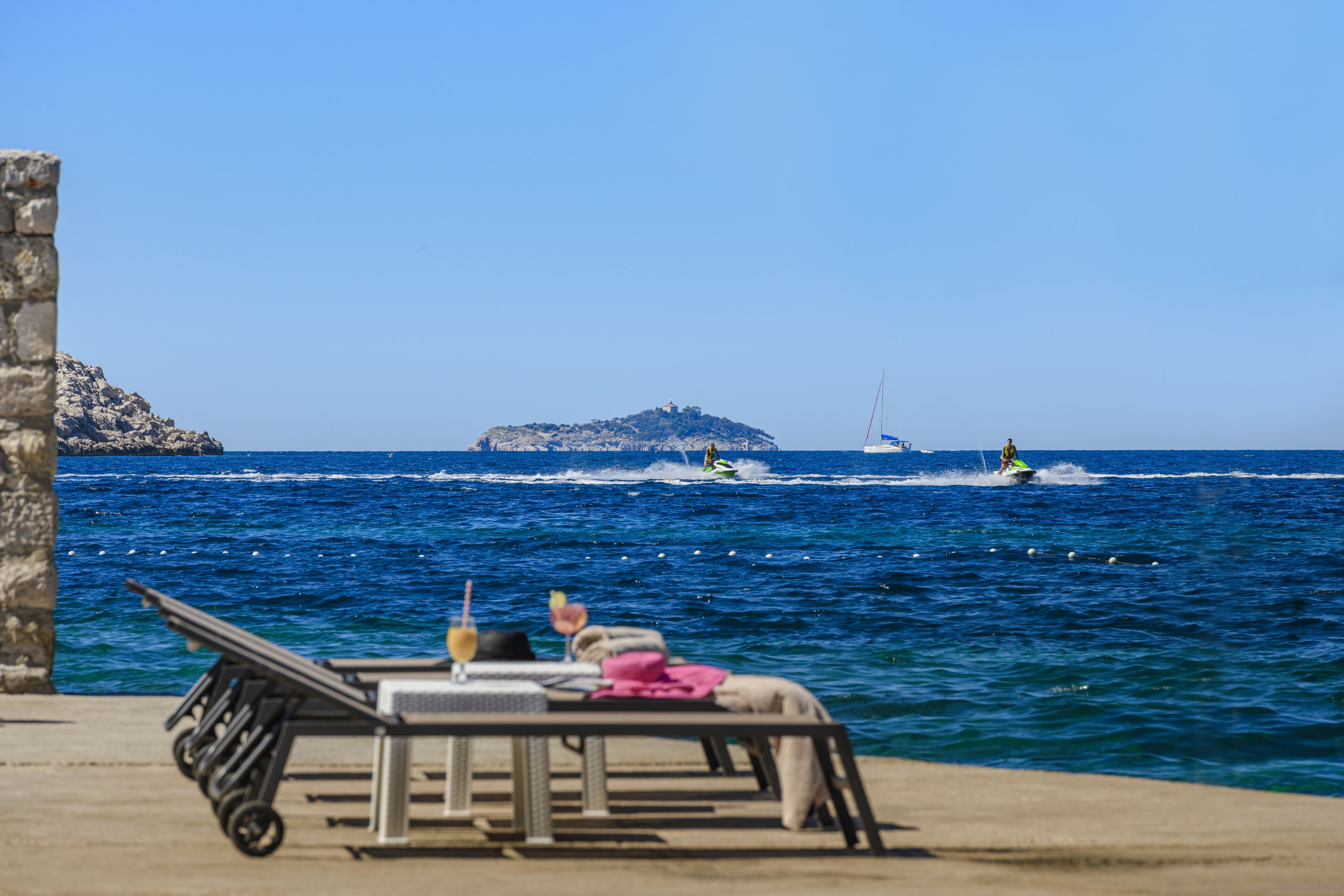 A seaside lounge with a view of the sea and a distant island.
