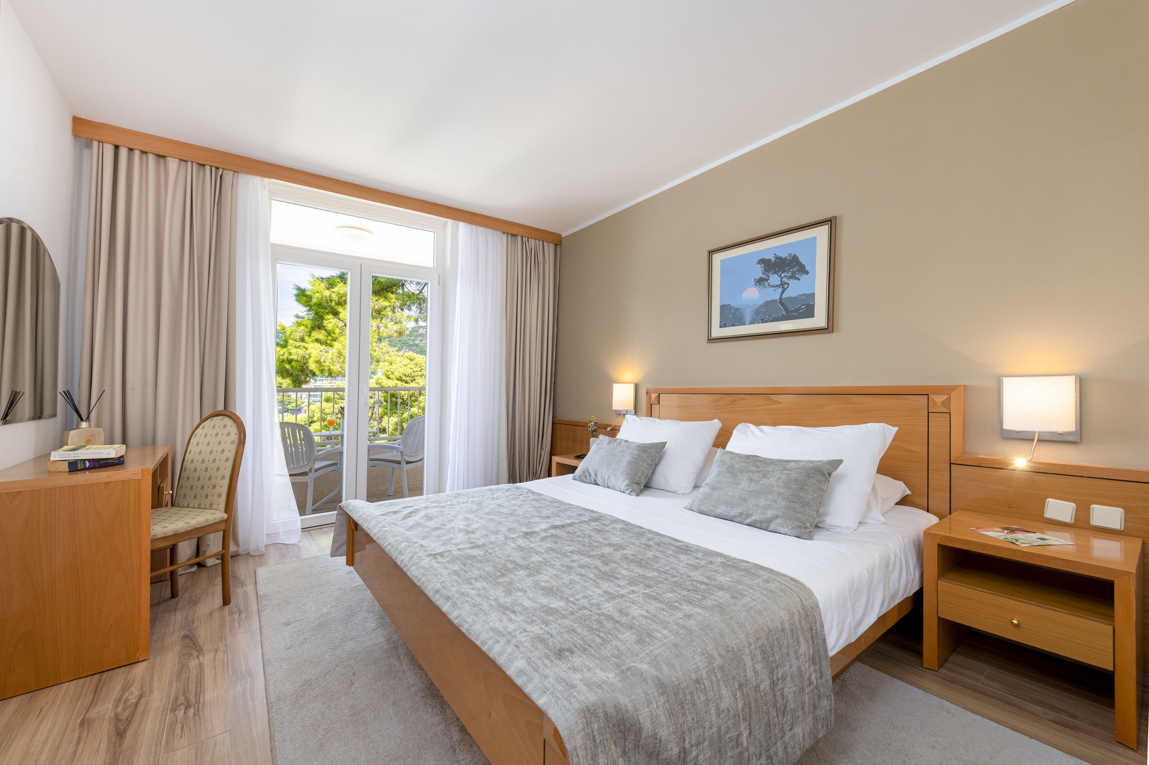 A hotel room with a large bed, a desk, a chair, and a view of the outdoors.
