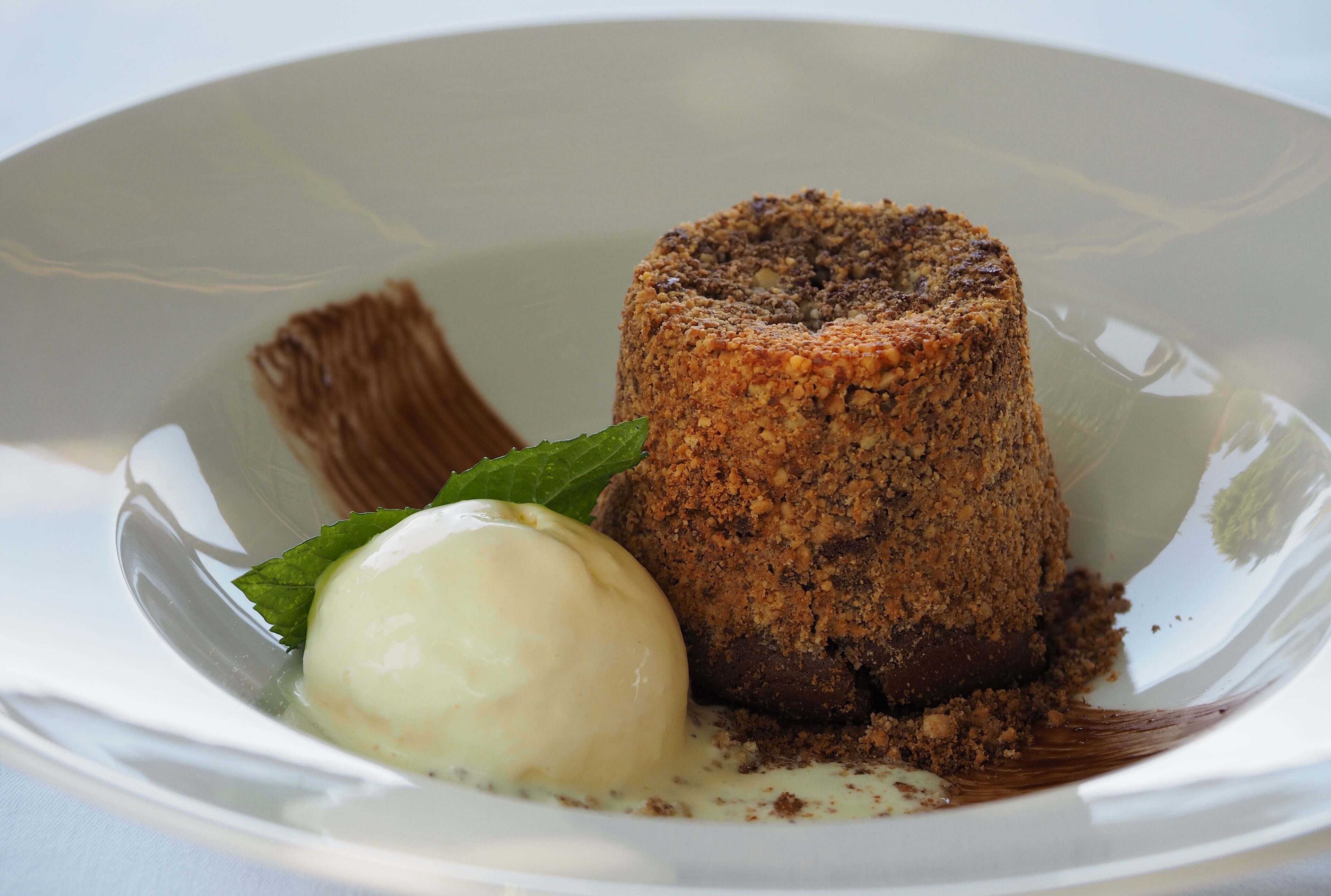 Dessert med smuldrende konsistens og en isbolle på en hvid tallerken.