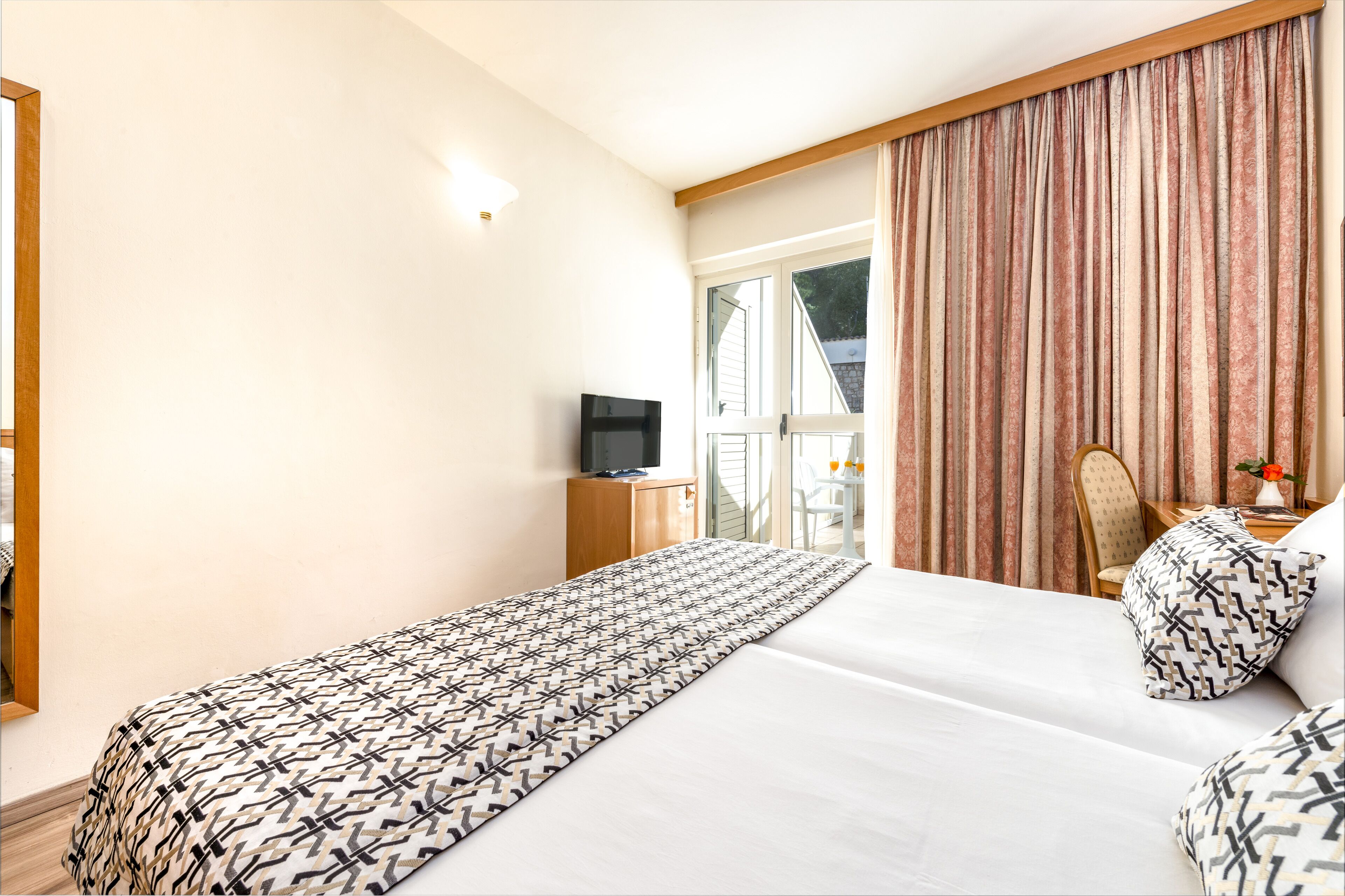 A hotel room with a bed, a TV, a desk, and a chair.