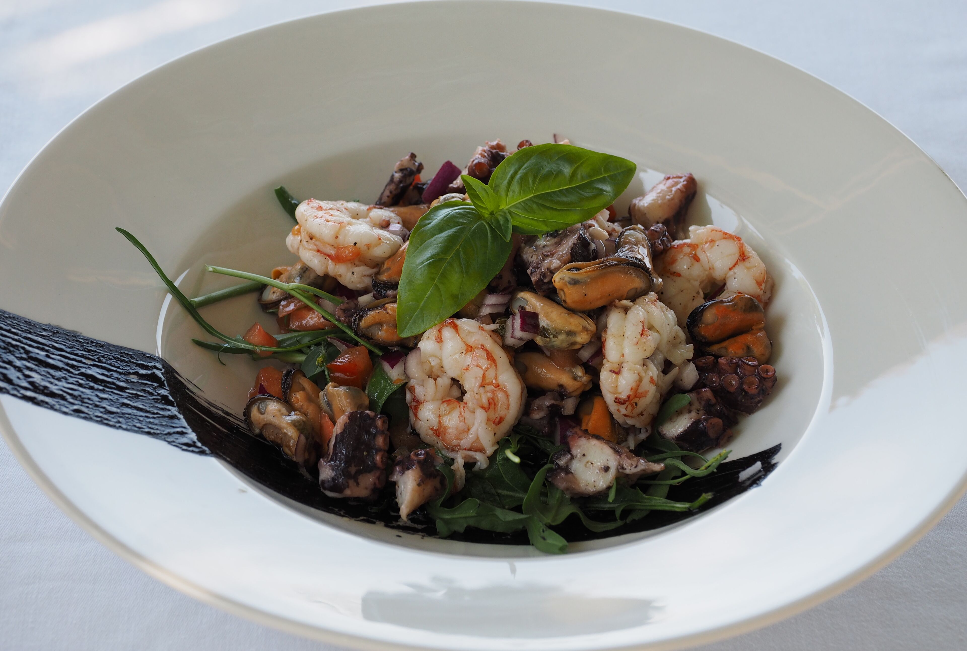 Une salade de fruits de mer composée de crevettes, de moules et de légumes verts.