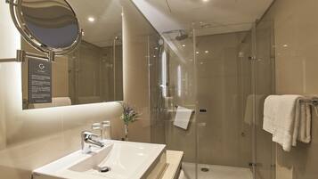 A modern bathroom with a glass-enclosed shower, a large mirror, and a white sink.
