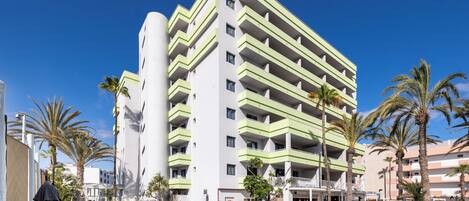A multi-story hotel with a pool area, palm trees, and outdoor seating.