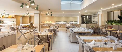 A modern dining area with multiple tables, a kitchen in the background, and a skylight above.