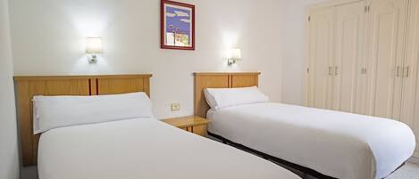 Two single beds with wooden headboards, bedside tables, and wall-mounted lamps.