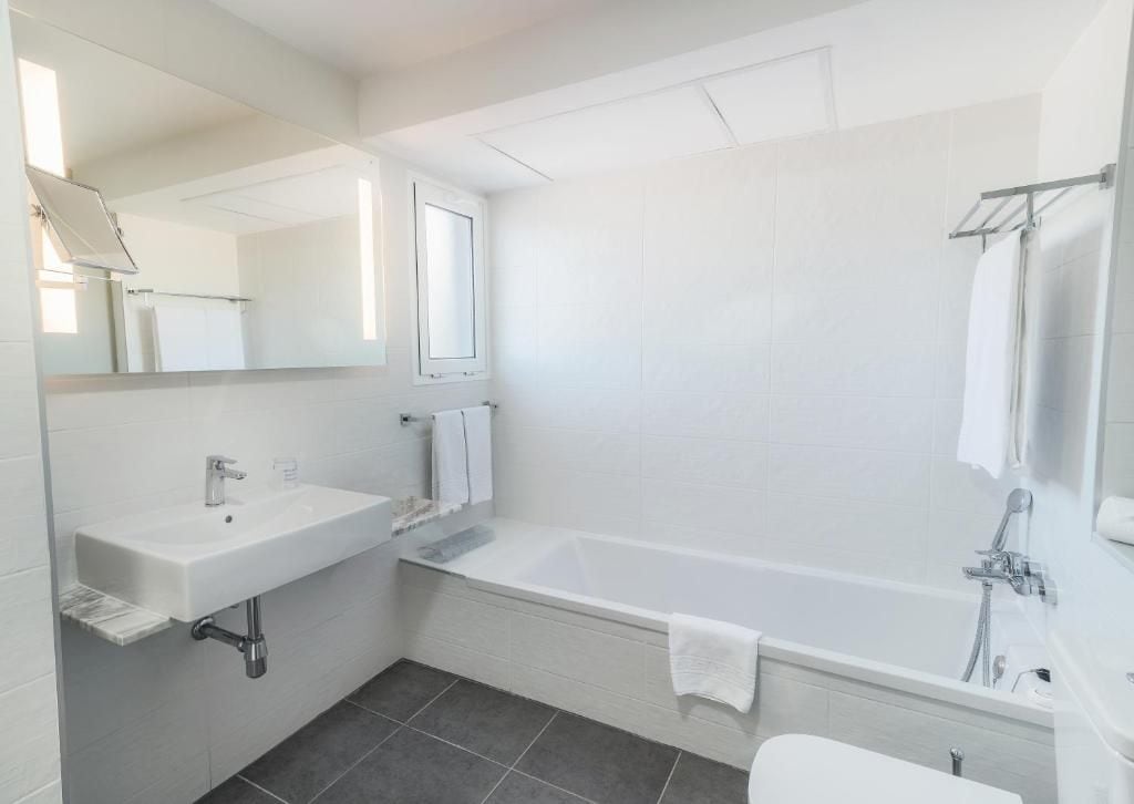 A modern bathroom with a white sink, a bathtub, and a toilet.