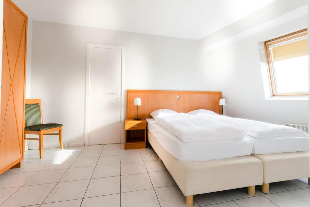 A bedroom with a bed, bedside table, chair, and wardrobe.