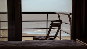 Habitación con vista al océano a través de una ventana con barandilla de metal.