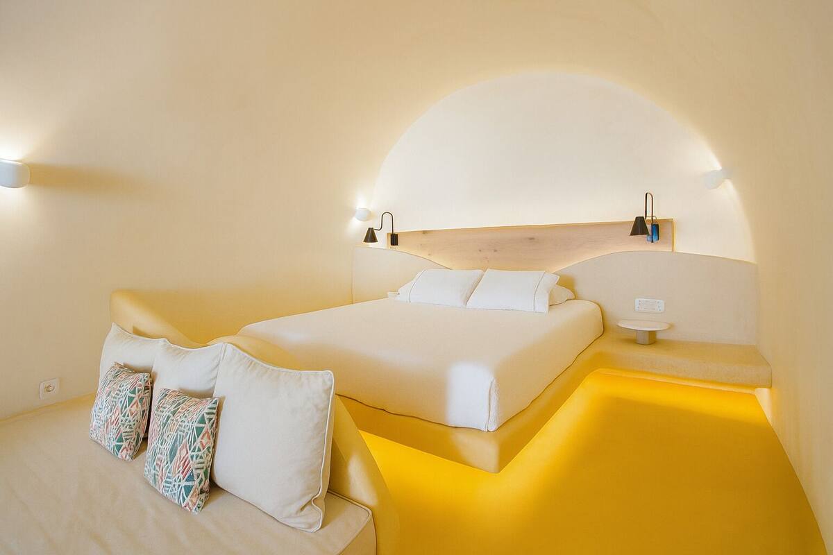 A modern bedroom with a bed, bedside tables, and a unique curved ceiling design.