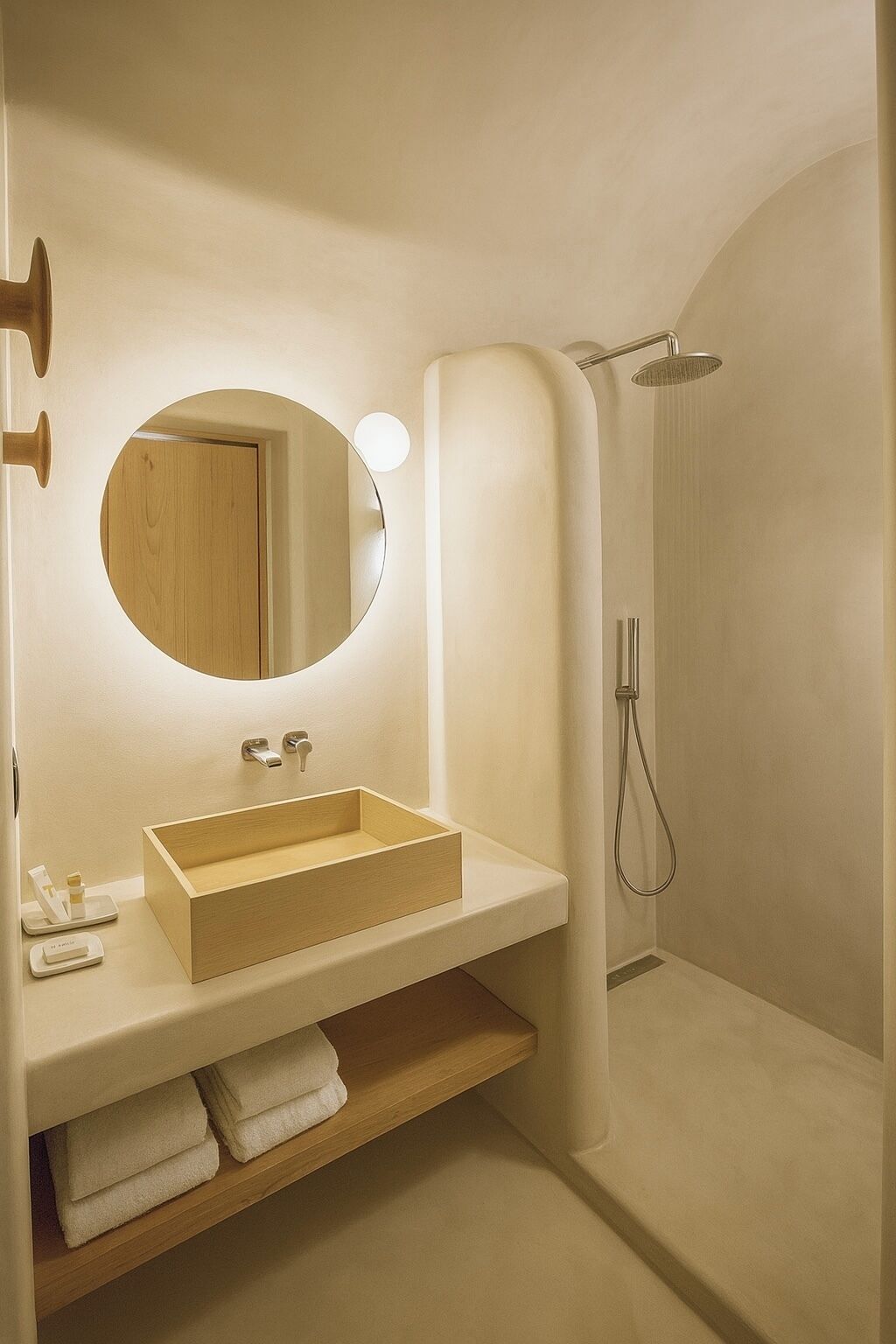 Une salle de bain moderne avec un meuble-lavabo en bois, un miroir rond et une douche.
