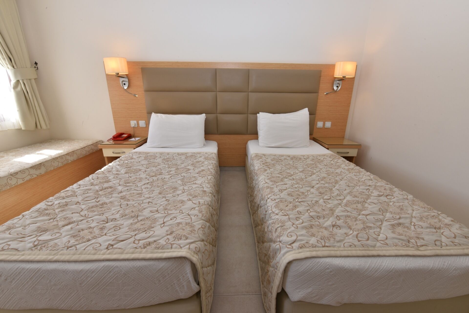A double bed room with a headboard, bedside tables, lamps, and a window with curtains.