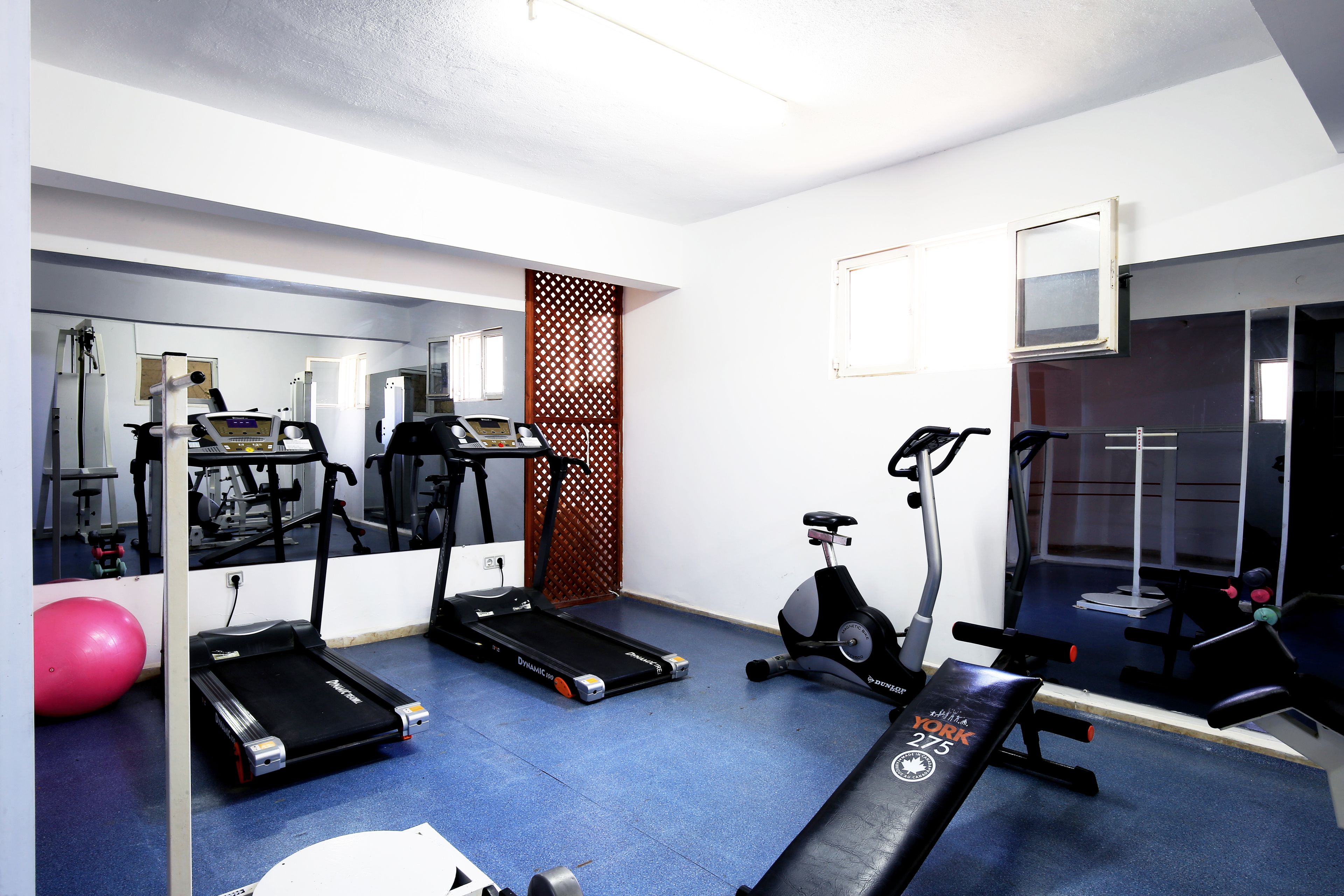 Een sportschool met loopbanden, een elliptische trainer en een bank.