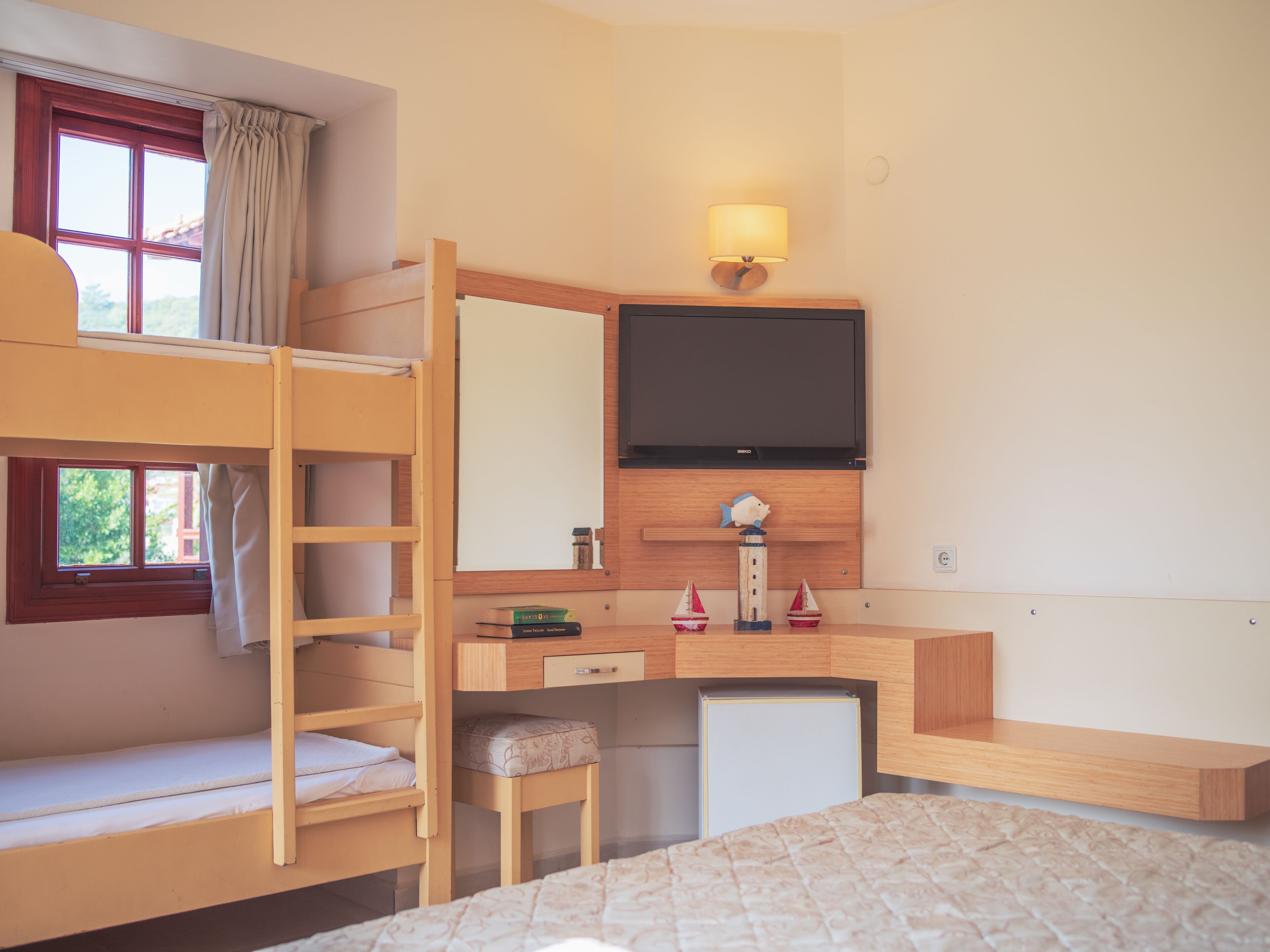 A bunk bed room with a desk, a television, and a small ship decoration.