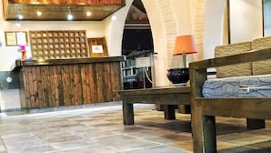 A reception area with a wooden reception desk, a bench, and a tiled floor. - Hotel Sea Bird (Corfu)