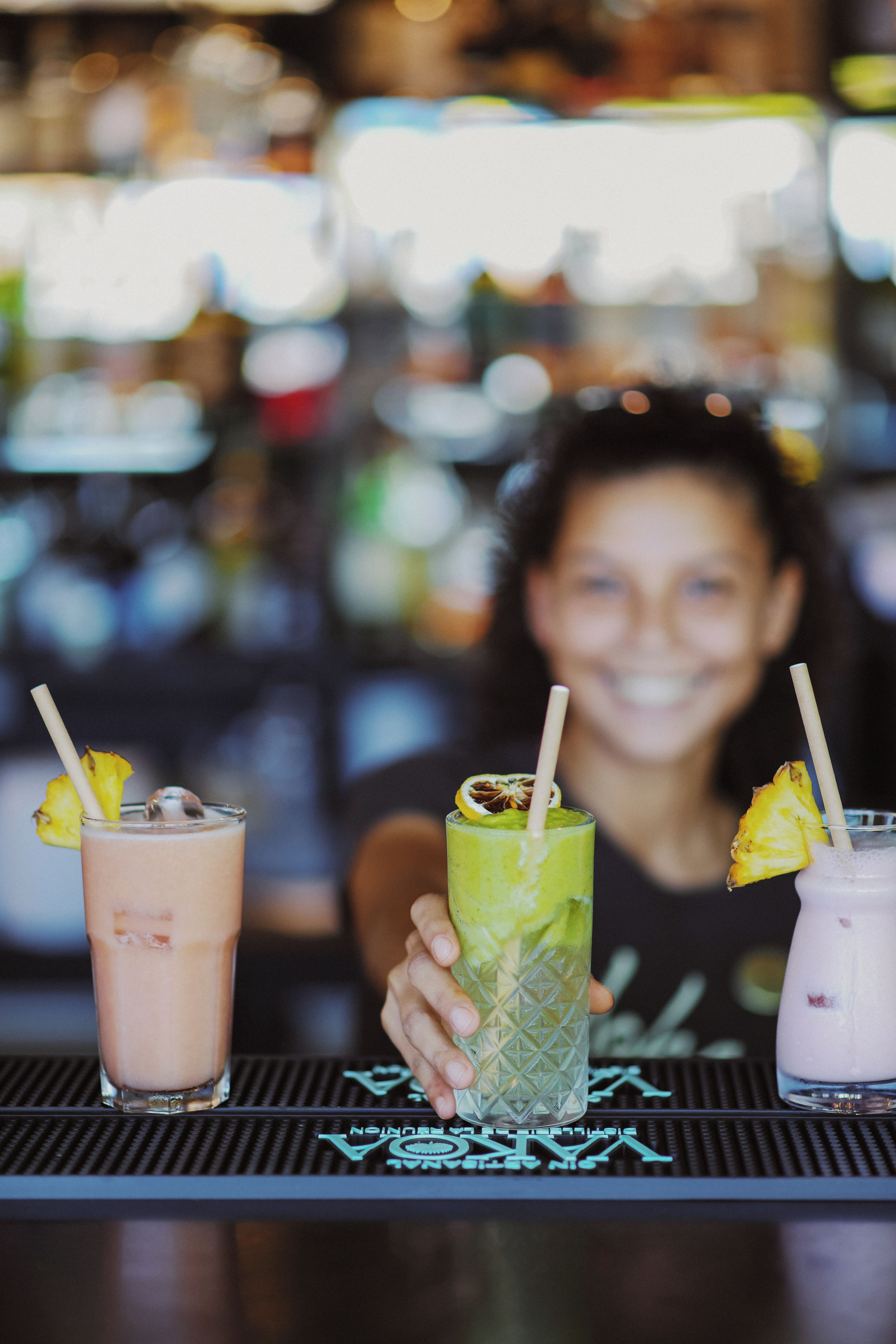 A bar with three drinks, each with a straw and a slice of fruit.