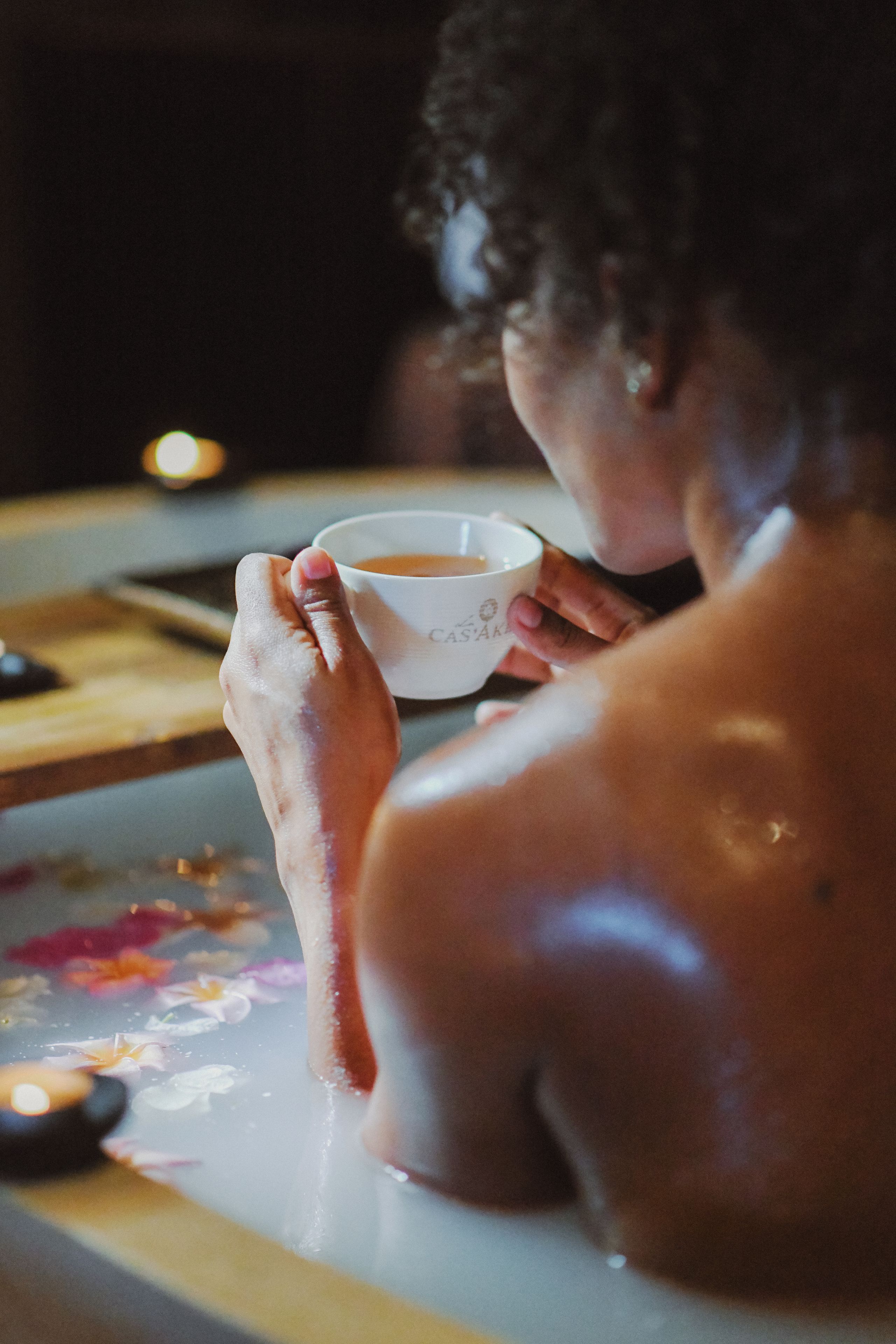Une personne dans une baignoire, tenant une tasse de thé.