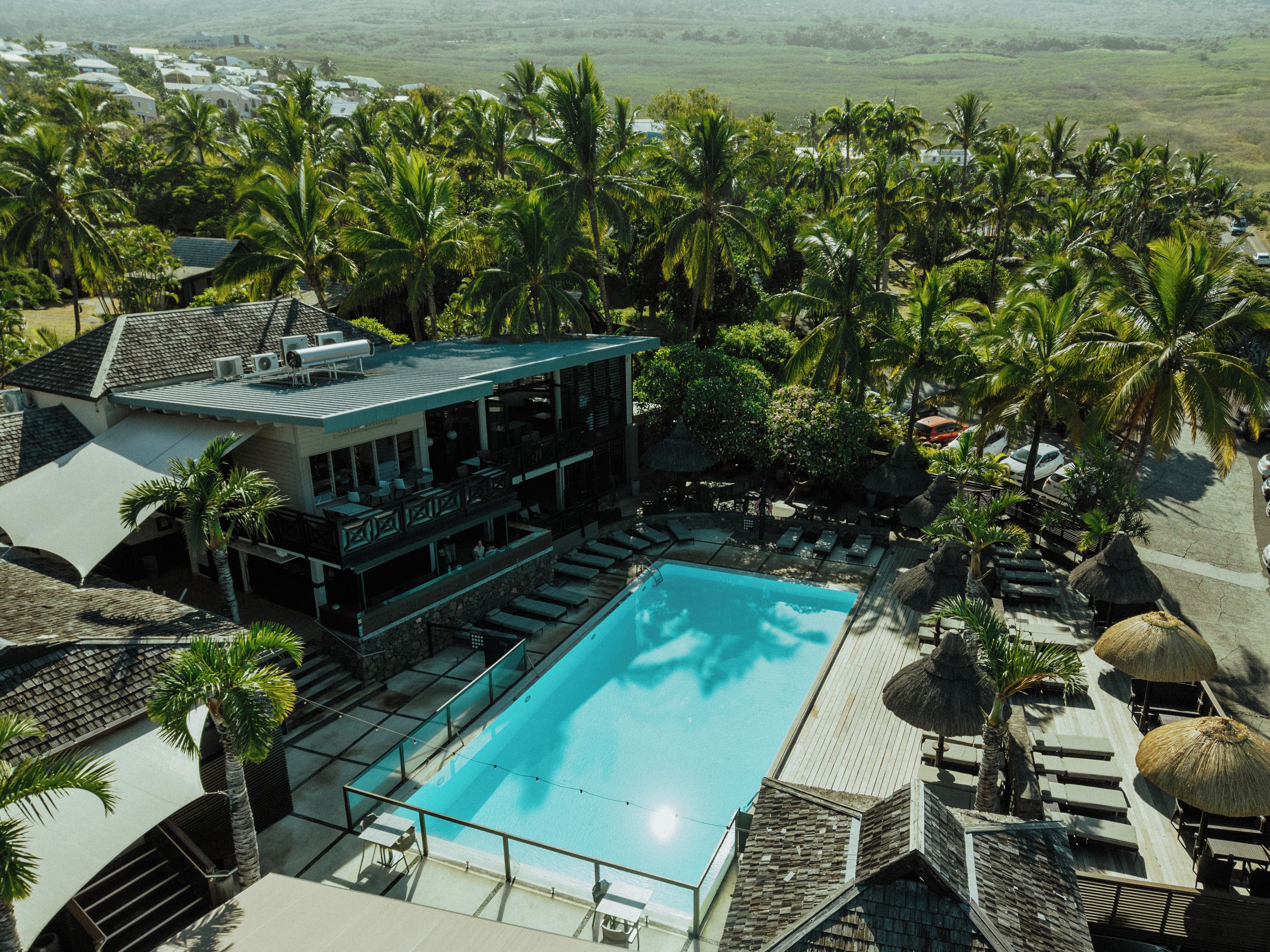A resort with a swimming pool, lounge chairs, and a view of the surrounding landscape.