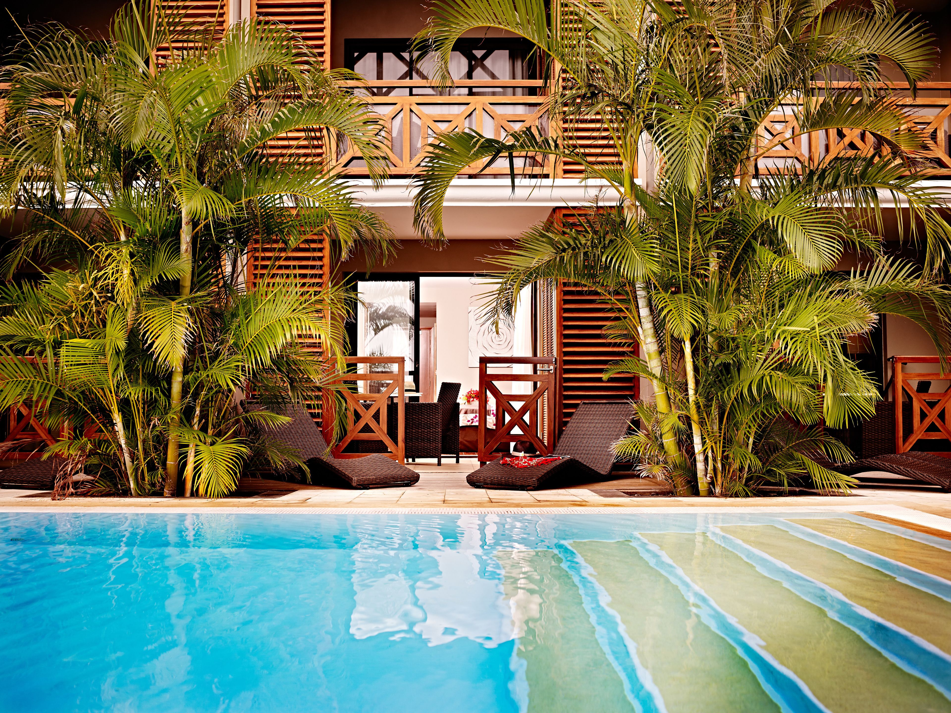A pool area with lounge chairs and a view of a building with wooden balconies.