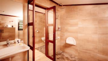 A modern bathroom with a large mirror, a sink, a toilet, and a shower area.