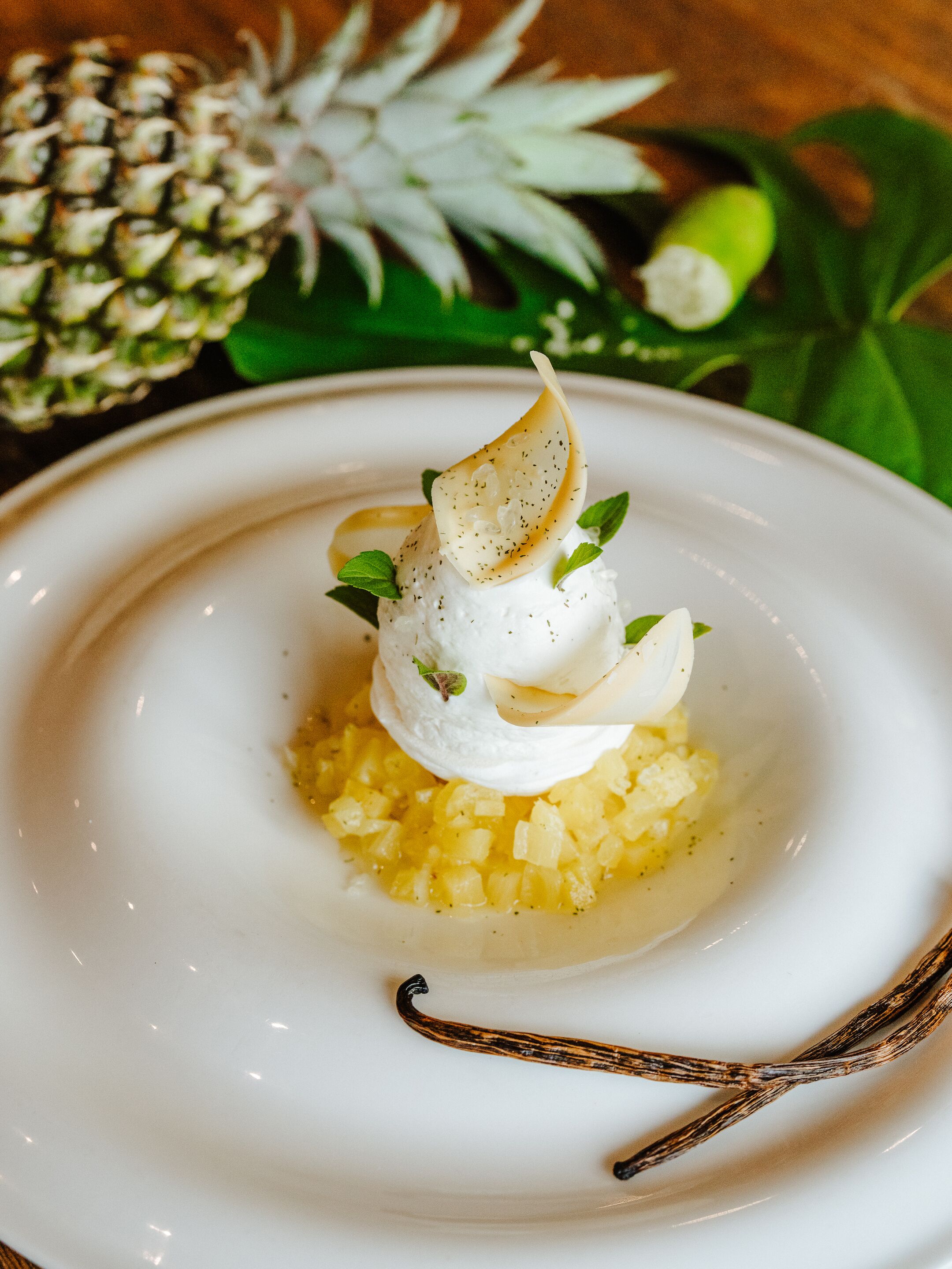 A dessert with whipped cream, a caramelized pear, and mint leaves on a plate.