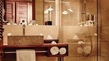 A modern bathroom with a glass-enclosed shower, a wooden vanity with a marble countertop, and a large mirror.