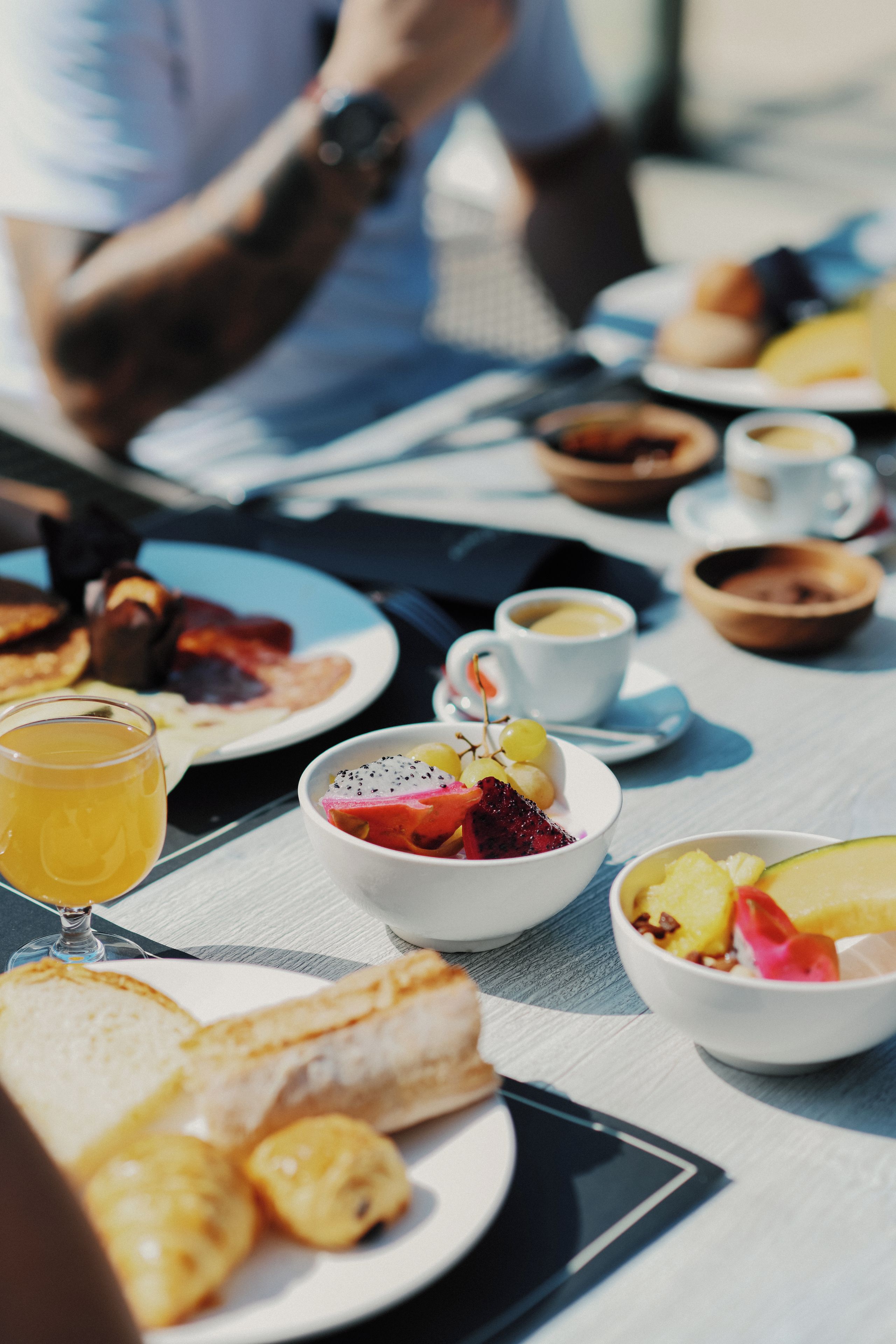 A breakfast setting with various dishes, including toast, fruit, and a cup of coffee.