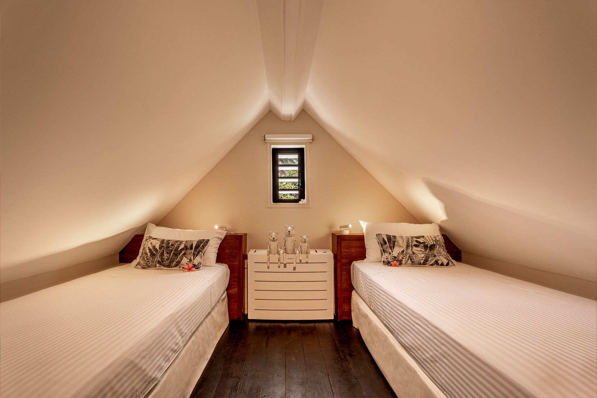 A bedroom with two beds, a dresser, a nightstand, a window, and a ceiling light.