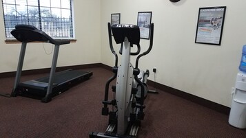 Gimnasio con cinta de correr, elíptica y dispensador de agua.