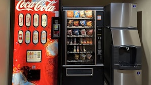 A vending machine with Coca-Cola and various snacks, a water dispenser, and a refrigerator. - Velkommen Inn (Clifton)