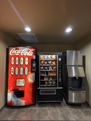 A vending machine with Coca-Cola and various snacks, a water dispenser, and a refrigerator. - Velkommen Inn (Clifton)