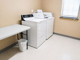 Un cuarto de lavandería con lavadora, secadora y una mesa.