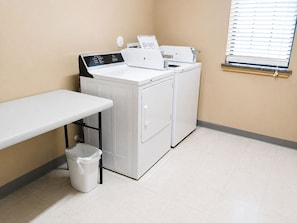 A laundry room with a washing machine, dryer, and a table.