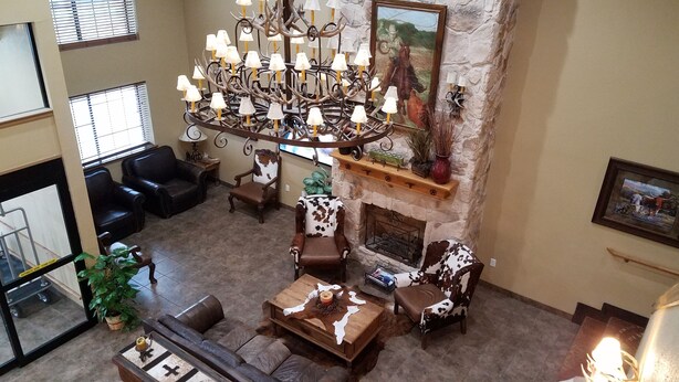 A spacious living room with a stone fireplace, leather sofas, a chandelier, and a large window. - Velkommen Inn (Clifton)