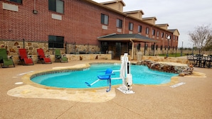 A swimming pool with a diving board, surrounded by lounge chairs and a brick building in the background. - Velkommen Inn (Clifton)