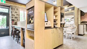 A modern bar area with wooden cabinets, a counter with a computer, and bar stools. - Hôtel Atypiq (Québec City)