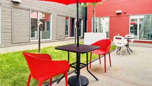 An outdoor seating area with a red umbrella, red chairs, and a table. - Hôtel Atypiq (Québec City)