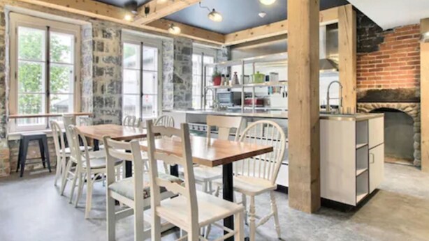 A rustic kitchen with a brick wall, wooden beams, and a stone fireplace. - Hôtel Atypiq (Québec City)