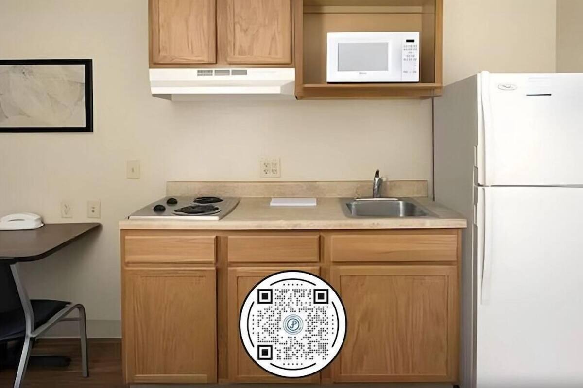 A kitchen with wooden cabinets, a microwave, a stove, a sink, and a refrigerator.