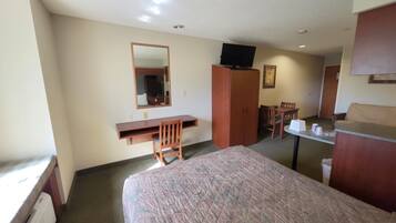 A hotel room with a bed, a desk, a chair, a television, and a small table.