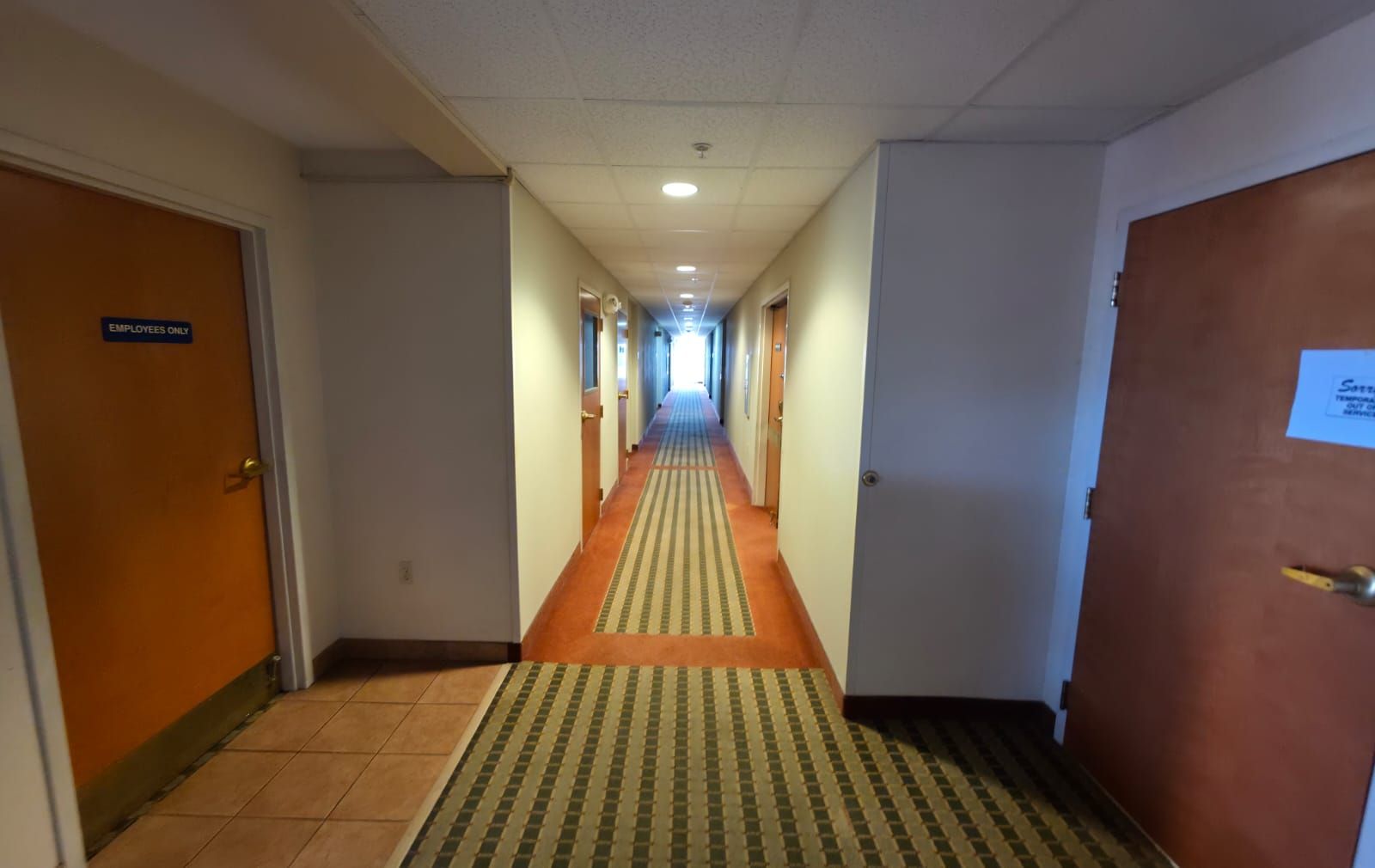 Un pasillo de hotel con puertas que indican 'Solo personal' y un cartel que muestra 'Entrada de servicio'.